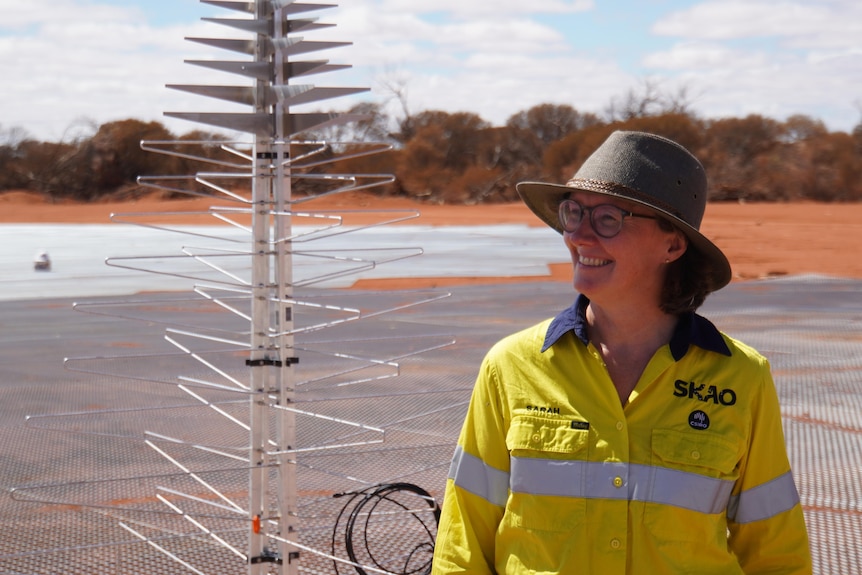 A woman named Sarah Pierce stands next to a smiling metal structure. 